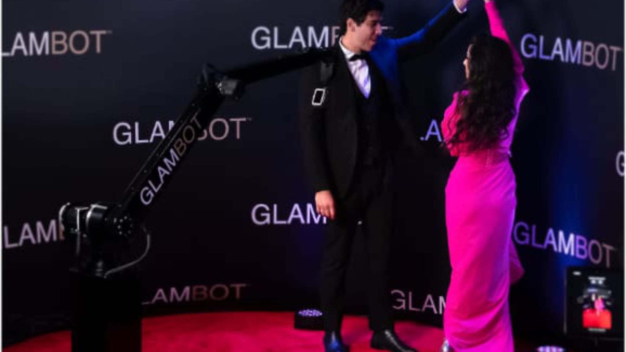 Guests posing beside the Glambot robotic camera arm at a formal event